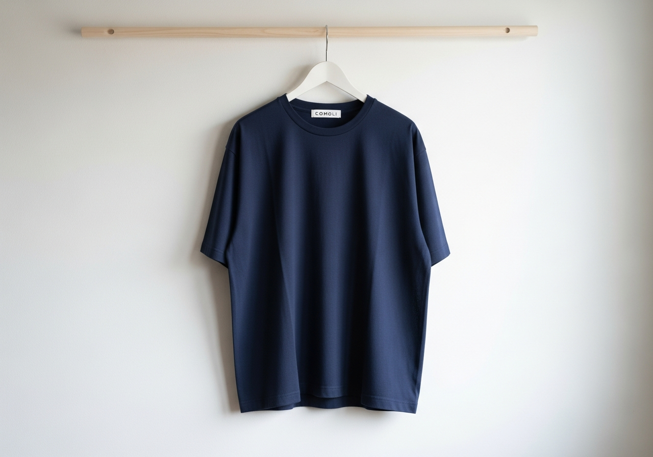 ComoliのTシャツが白い壁にかけられている様子